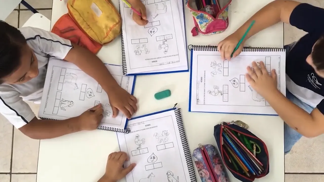 Children doing schoolwork at a table with books and pencils