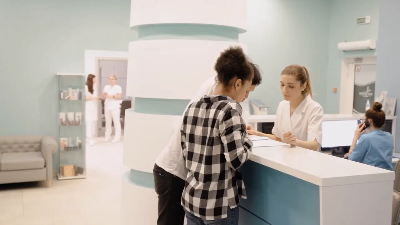Patient standing at a reception desk in a bright medical office