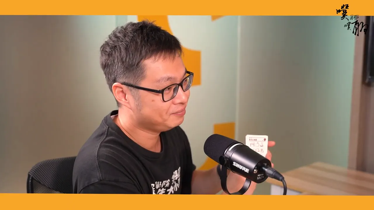 講者在麥克風前展示單張圖解筆記卡牌,卡面上有象徵圖示