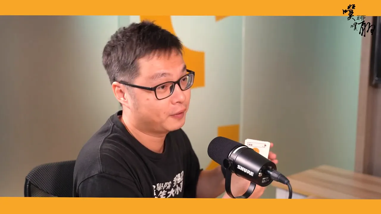 講者在麥克風前手持圖解筆記卡牌,卡牌正面與圖示可見