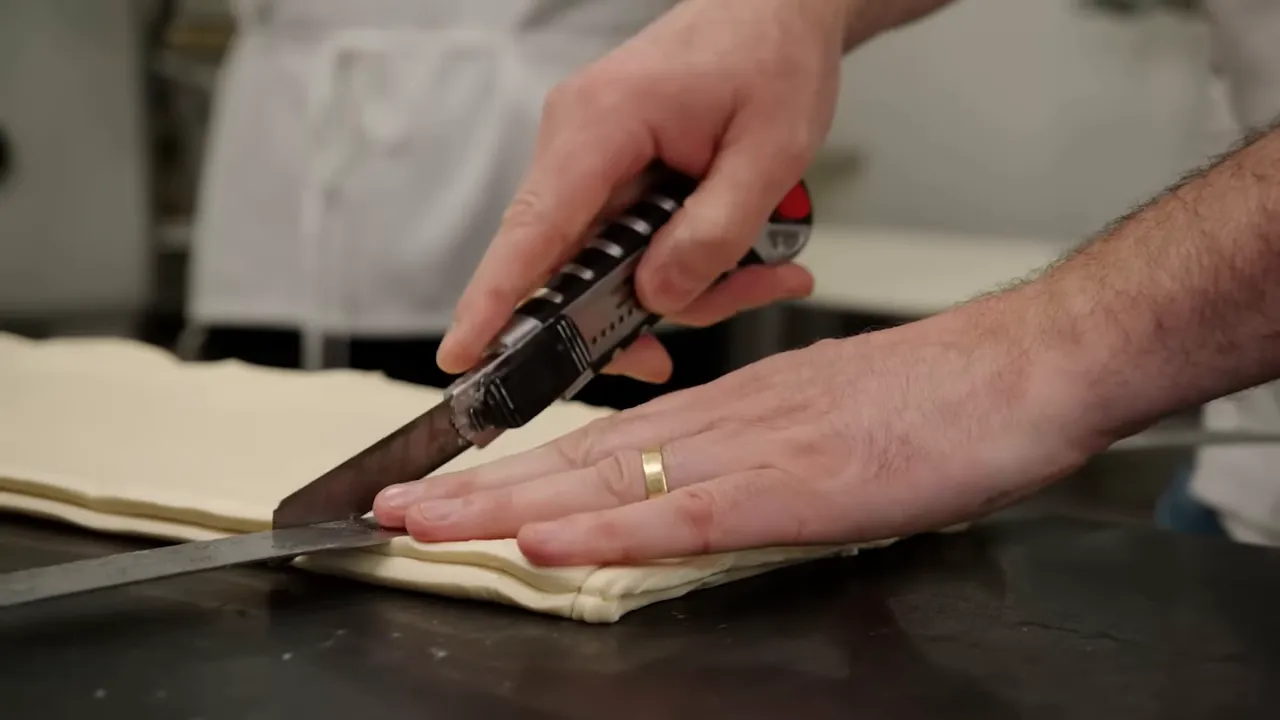 Razor cutting triangles from laminated dough showing distinct layers