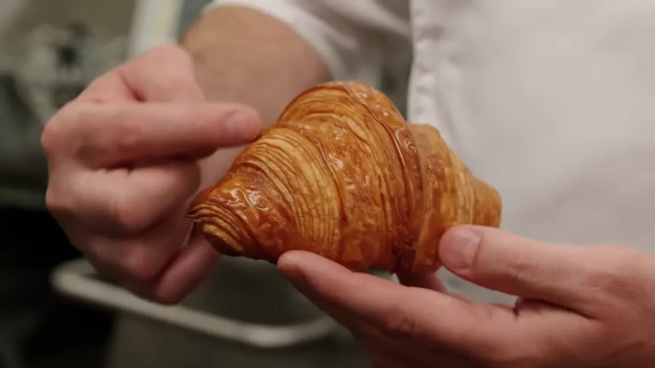 Golden croissant with separated flaky layers on a plate
