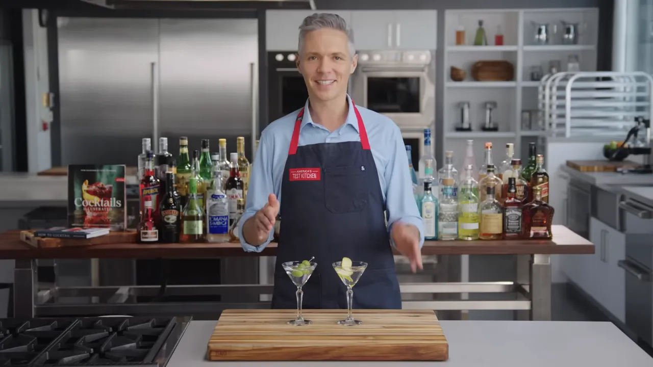 Host standing behind two garnished martinis in a test kitchen