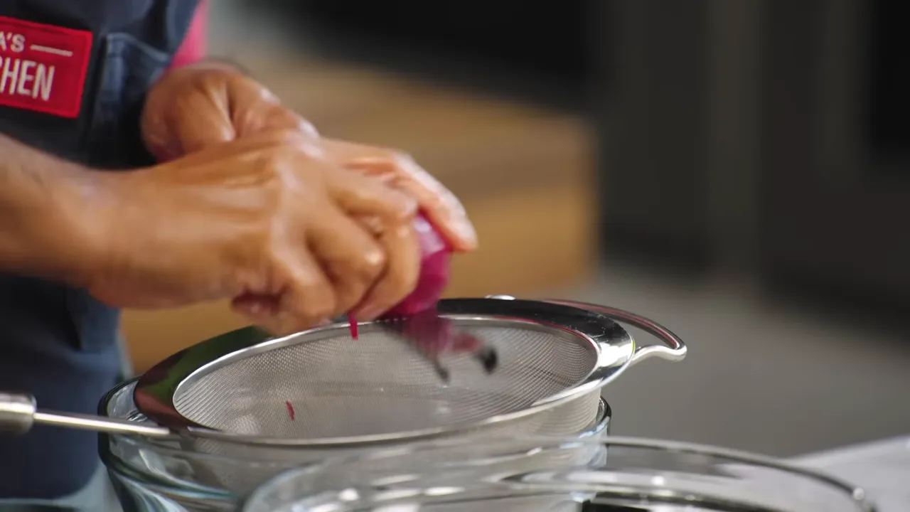 Grated beets being pressed through a strainer for beet juice