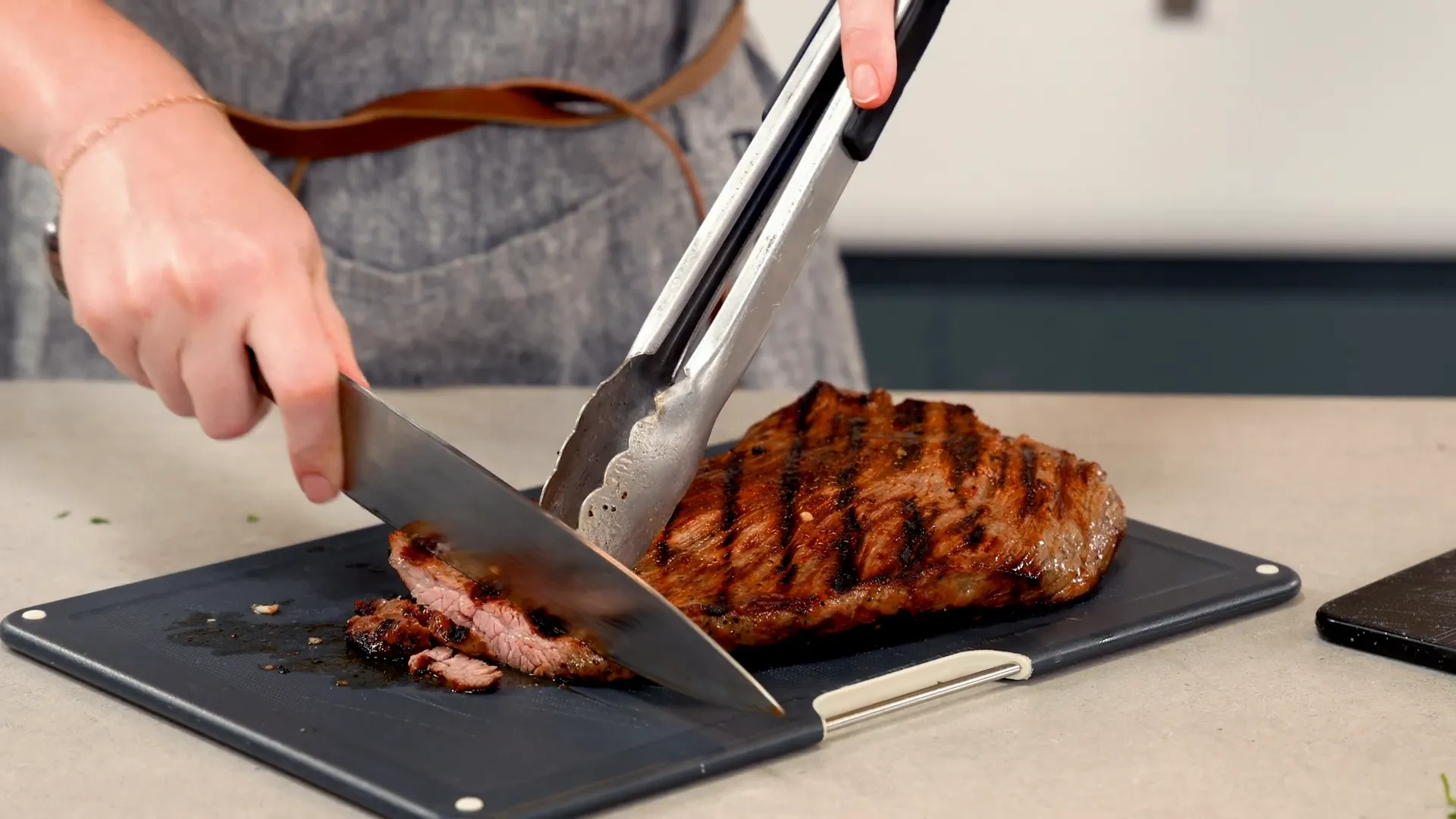 Slicing cooked carne asada against the grain