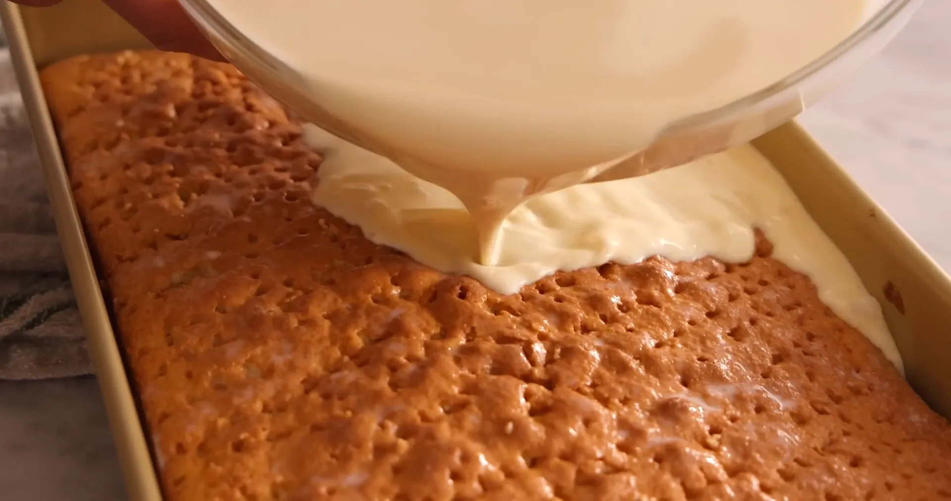 Poking holes in the warm cake to soak the milk mixture