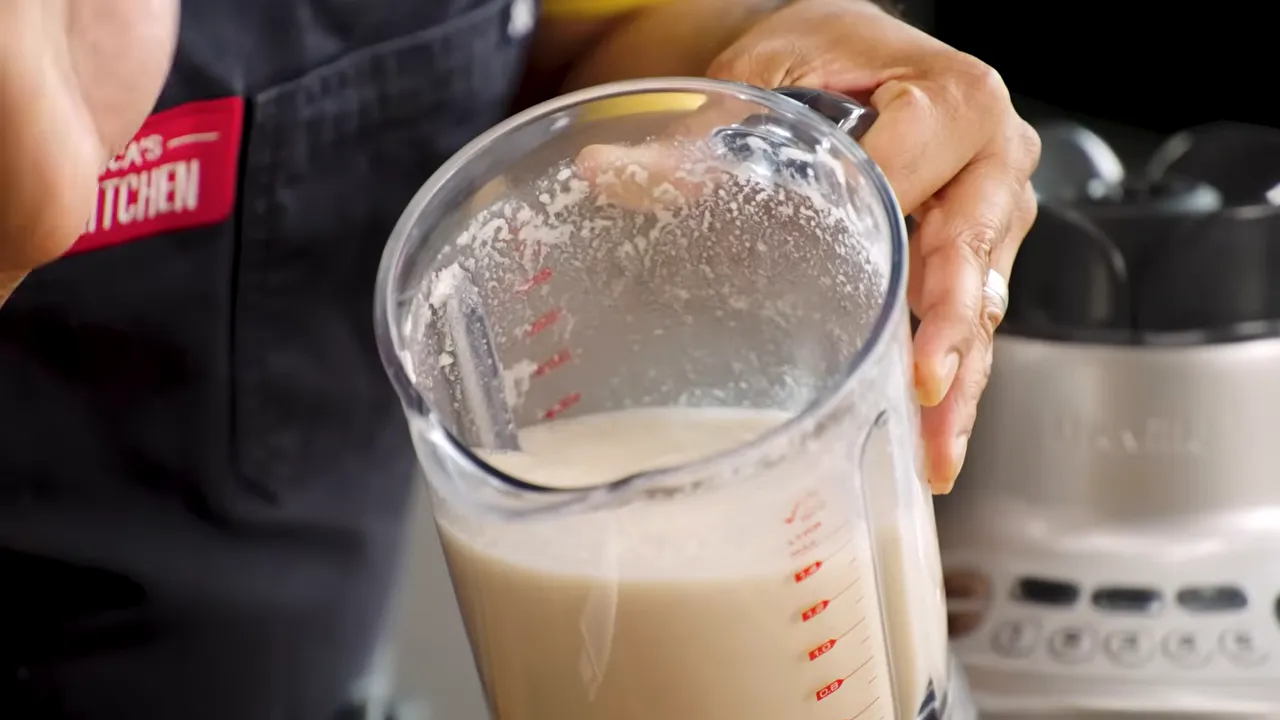 close-up blender jar with toasted coconut and coconut liquid ready to blend