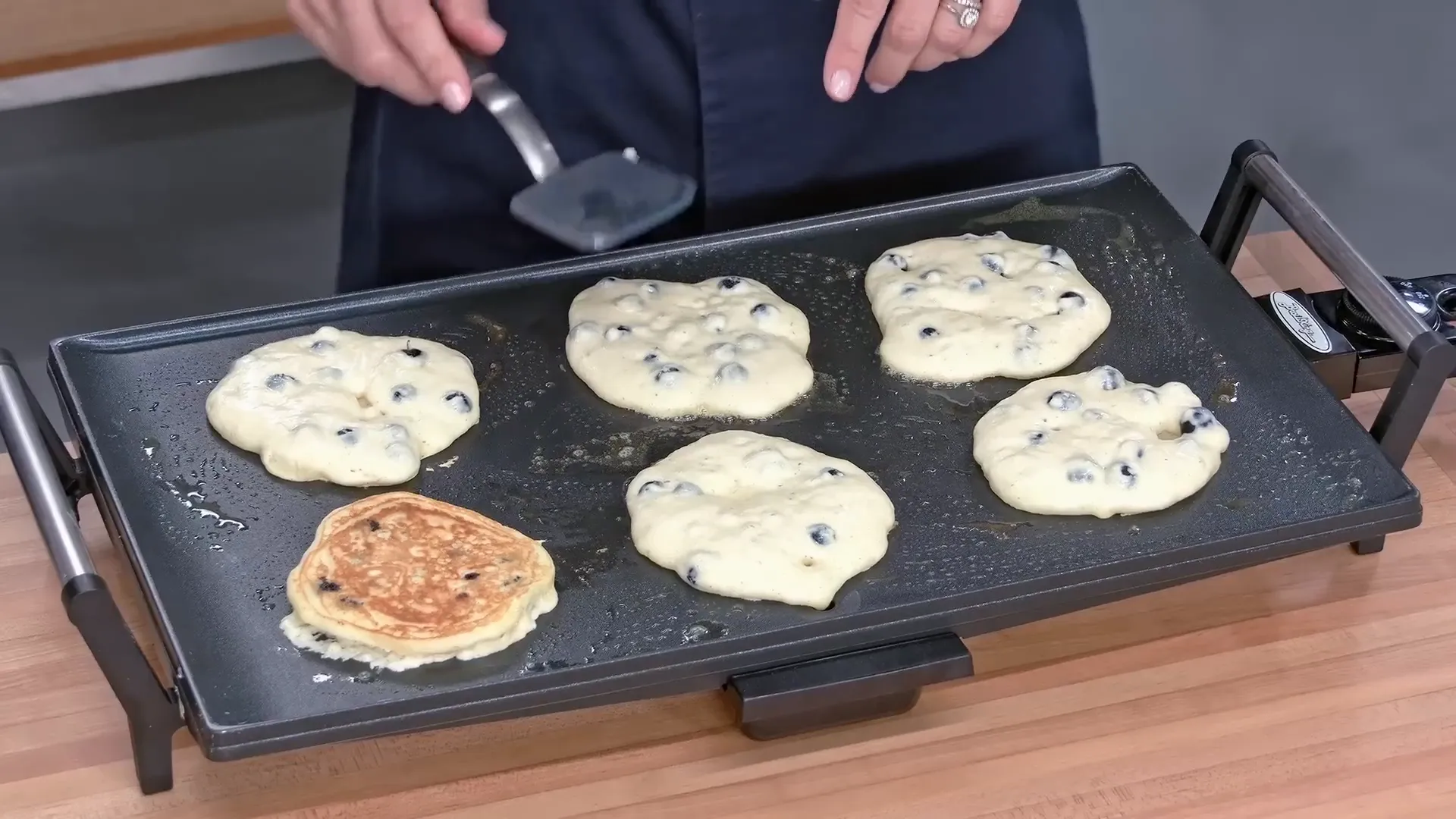 Golden brown blueberry pancakes cooking on griddle