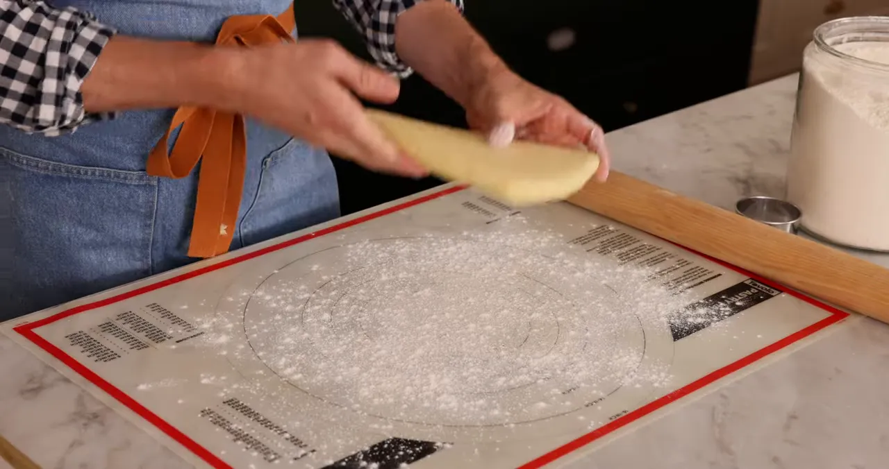 Rolling cookie dough to a quarter inch thickness on a pastry mat