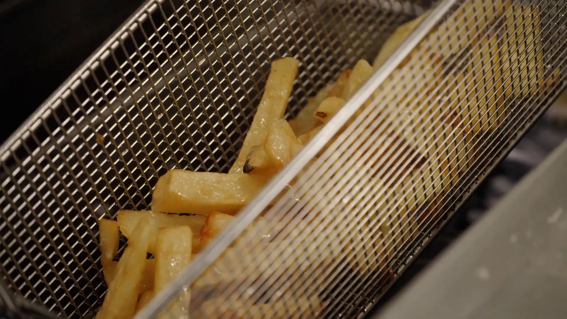 Partially fried chips with golden edges cooling before the second fry
