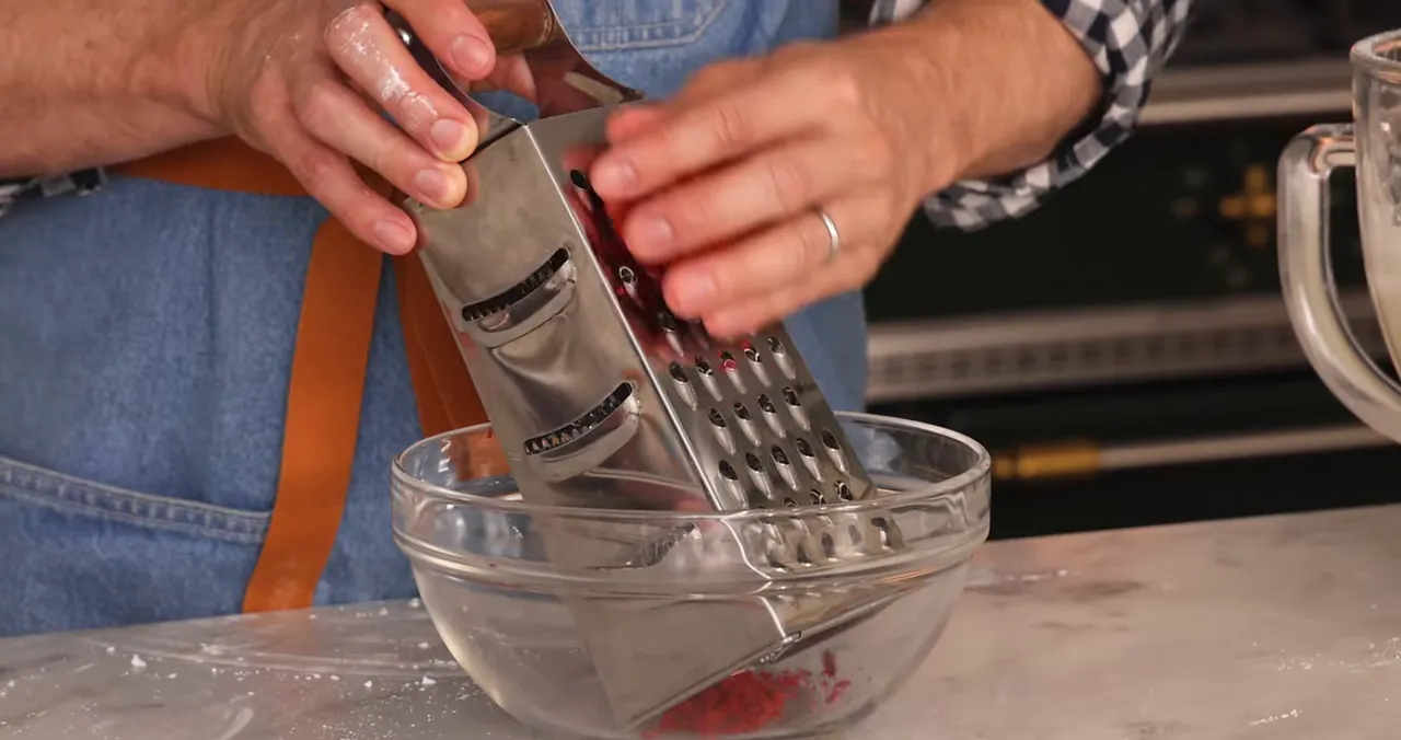Grating a small cake to create vibrant red crumbs