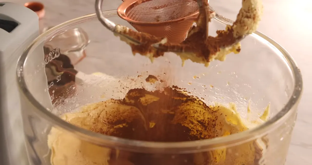 Sifting natural cocoa powder into the batter