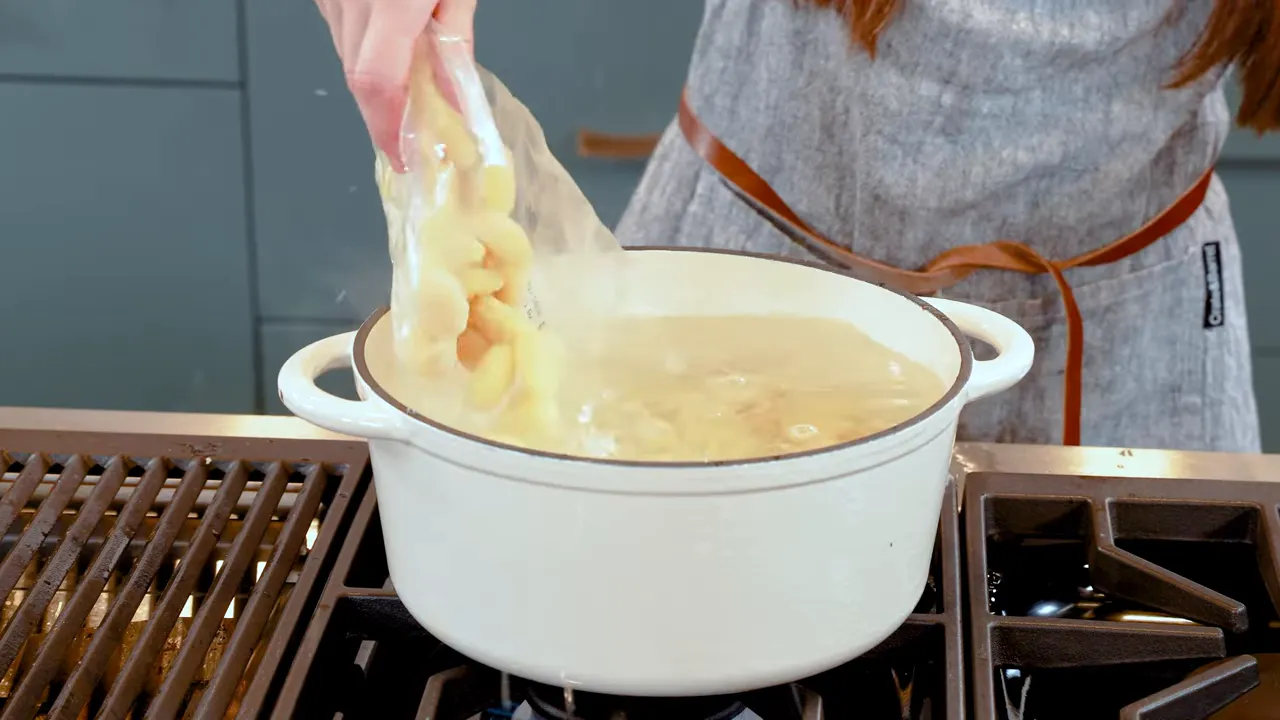 Pouring a single bag of packaged gnocchi into a pot of boiling water