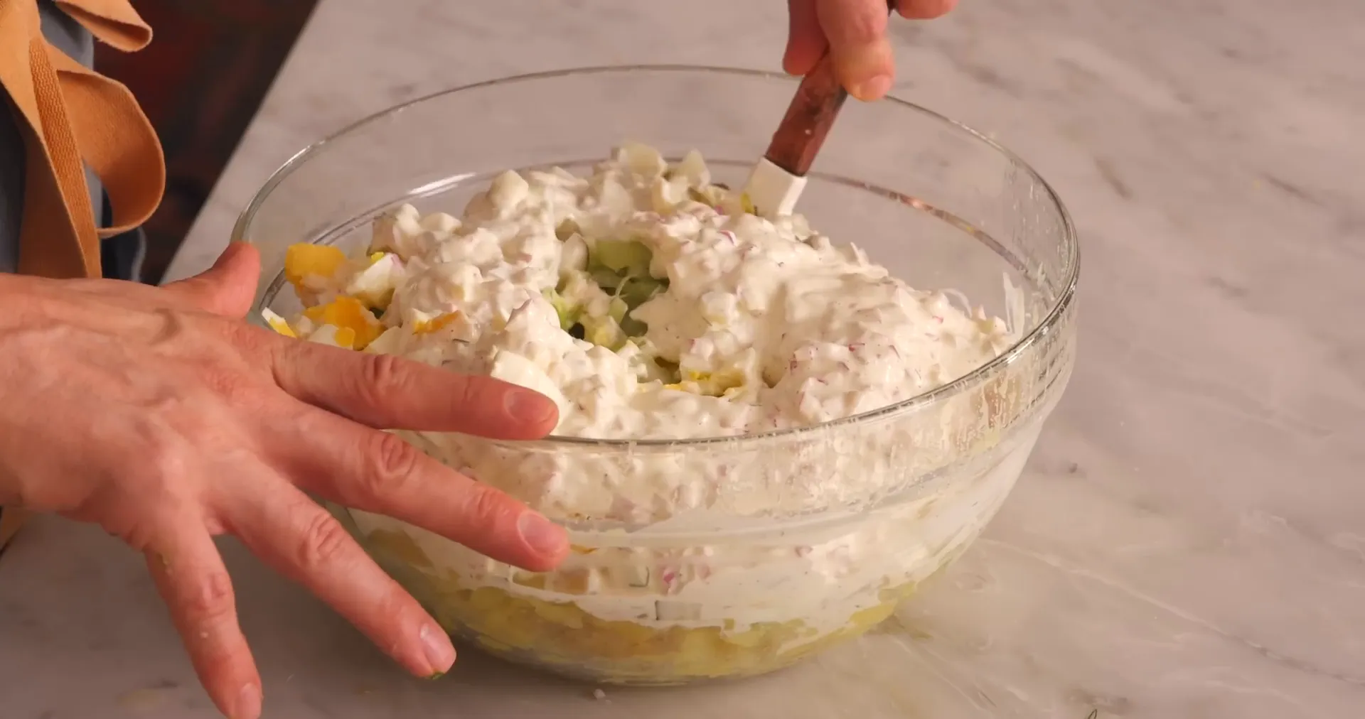 Mixing potato salad ingredients gently in a bowl