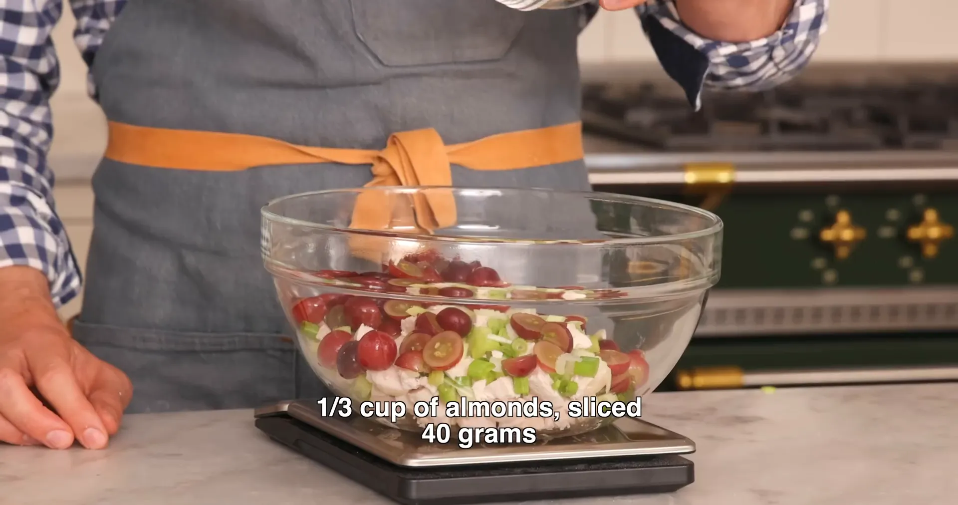 Mixing chicken, celery, grapes, and almonds in a large bowl