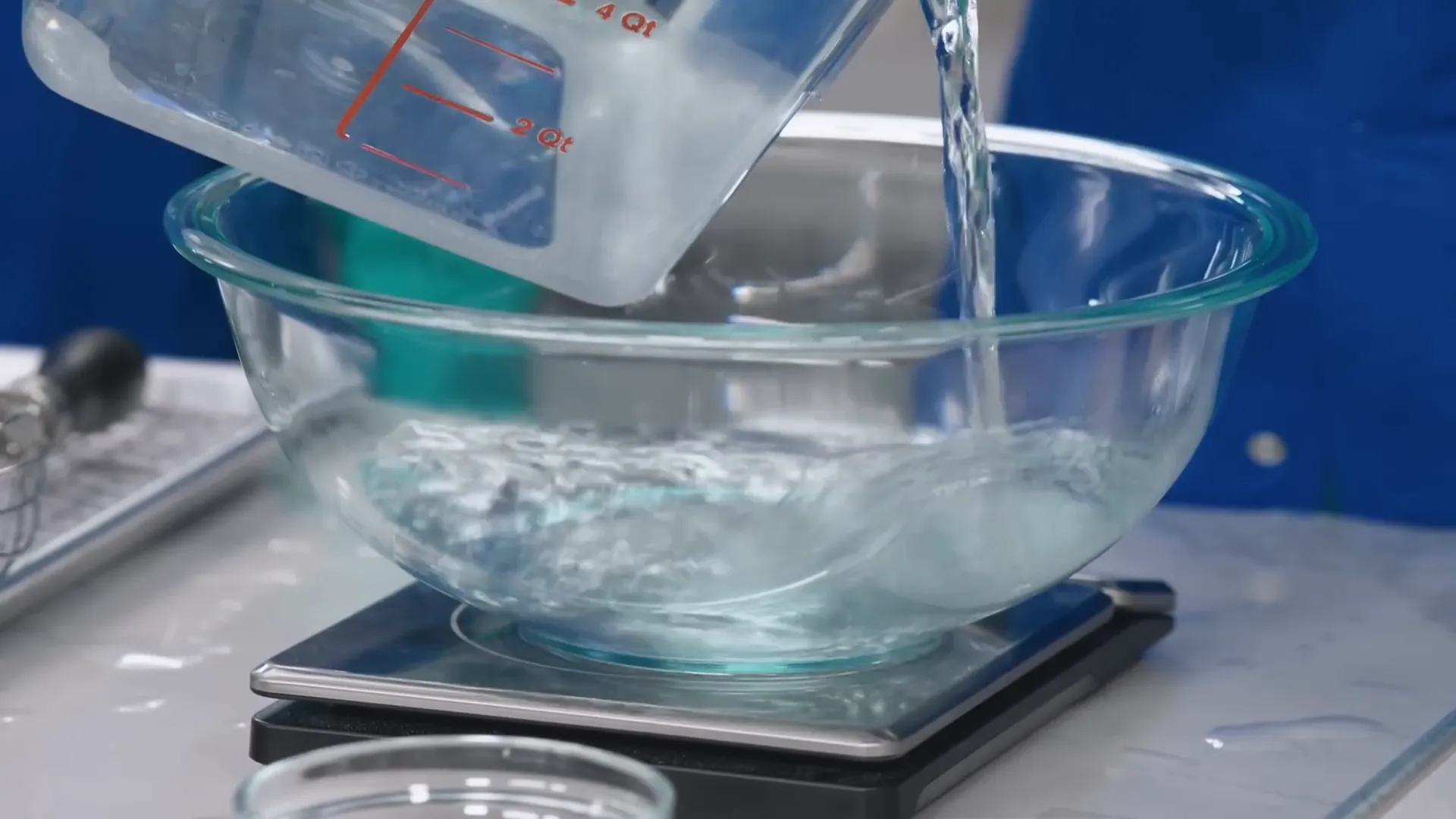 Pouring food-grade lye crystals into a bowl of water while wearing protective gloves