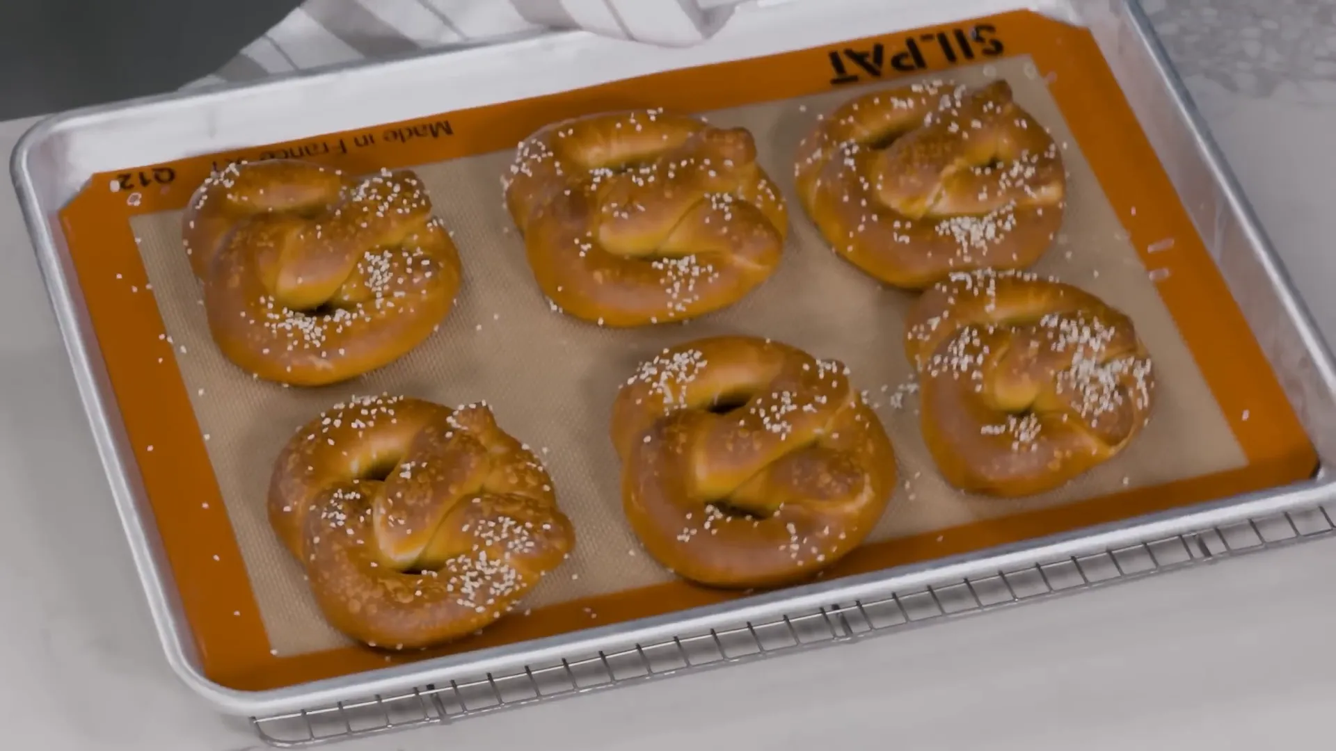 Finished dark-brown Bavarian pretzels cooling on a rack ready to eat