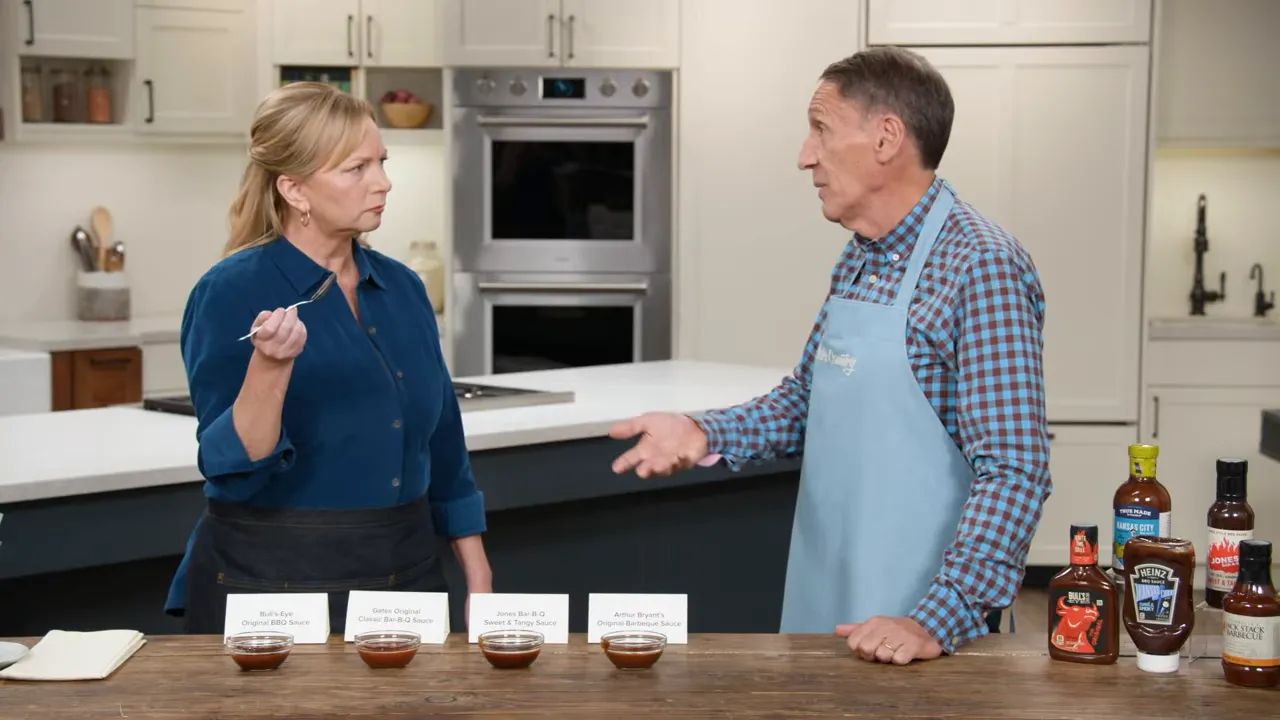 Two hosts at a kitchen counter with four labeled bowls of barbecue sauce arranged for a side-by-side tasting.