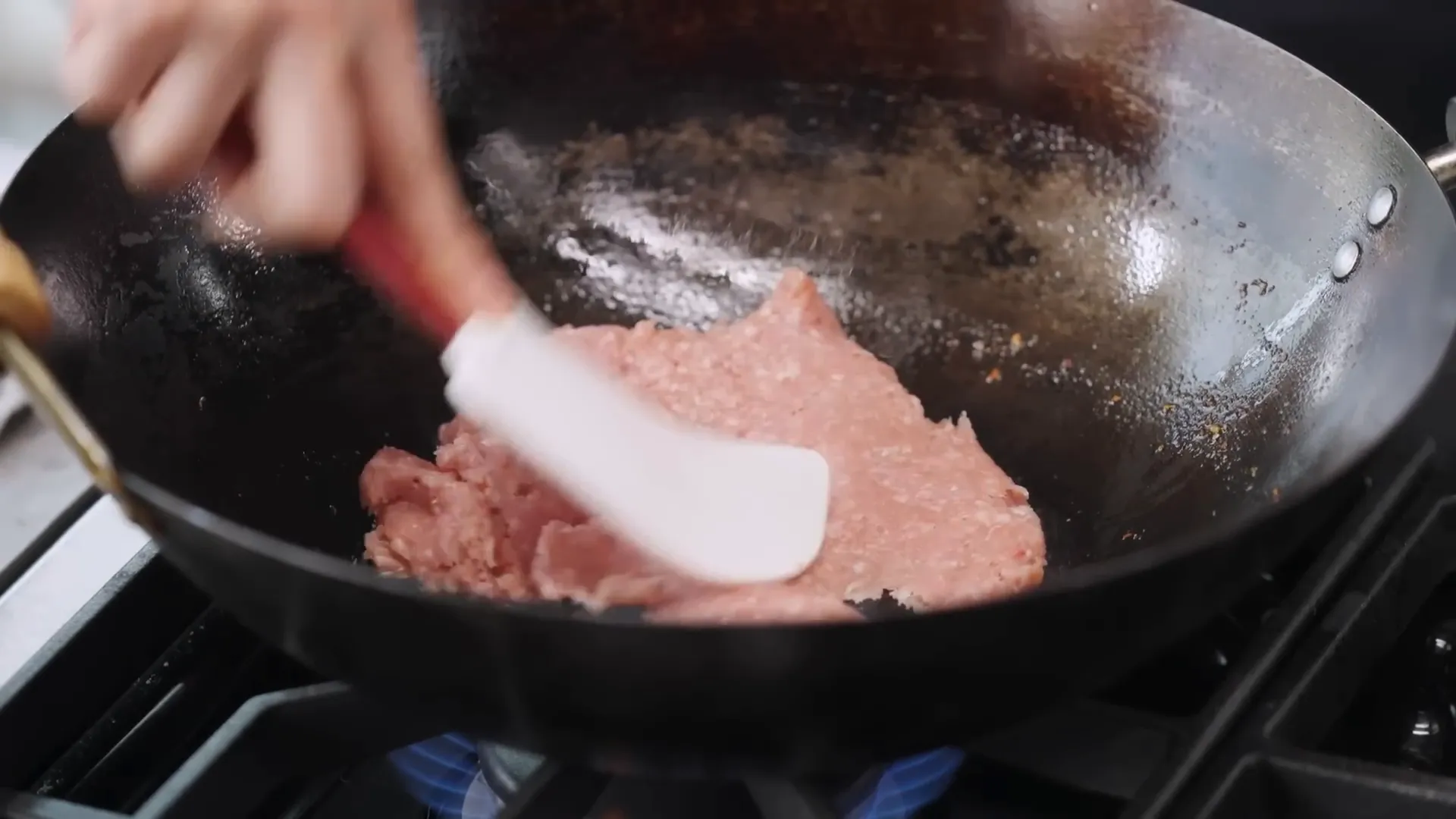 Smearing ground pork thinly in wok for maximum browning