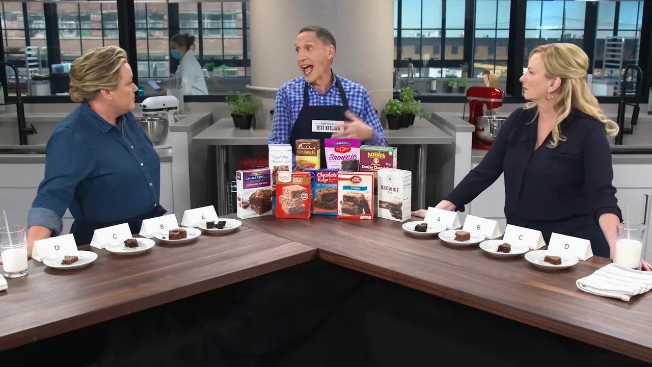 Full tasting setup showing hosts, the lineup of boxed brownie mixes in the center, and plated samples labeled A–D.