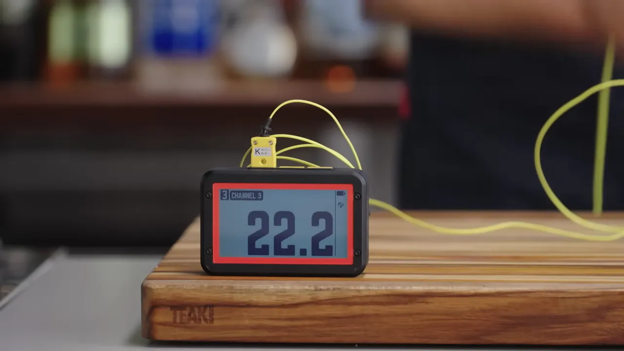 digital thermometer on a wooden board showing 22.2°C with yellow probe wires