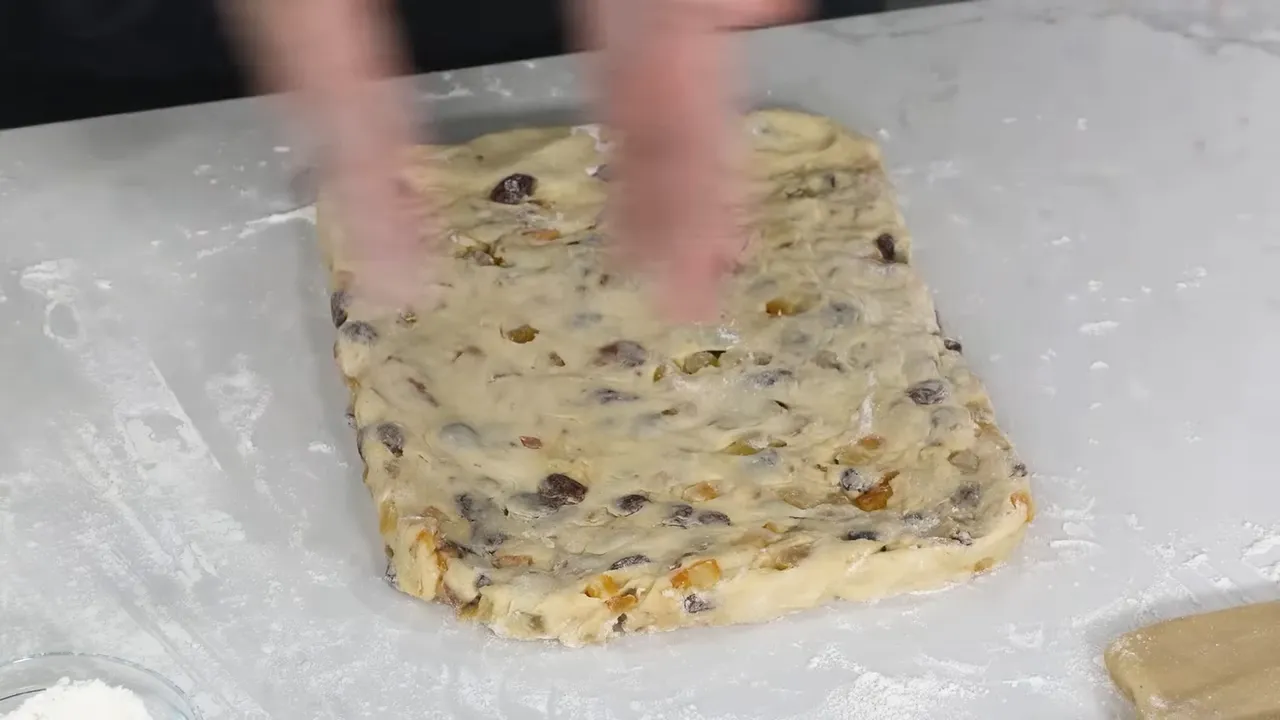 Top-down view of stollen dough pressed into a rectangular shape with visible raisins and candied peel