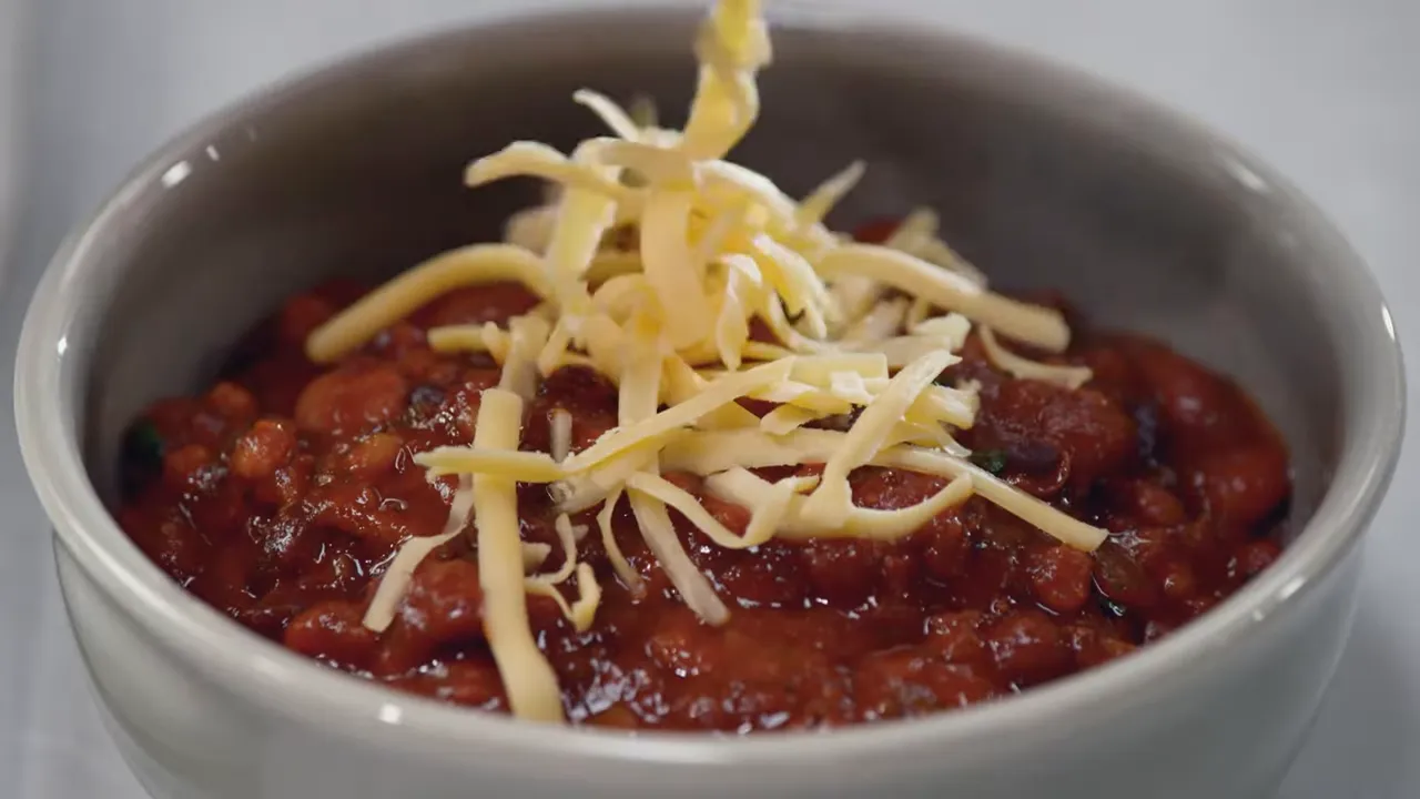 shredded cheese falling onto a bowl of vegetarian chili