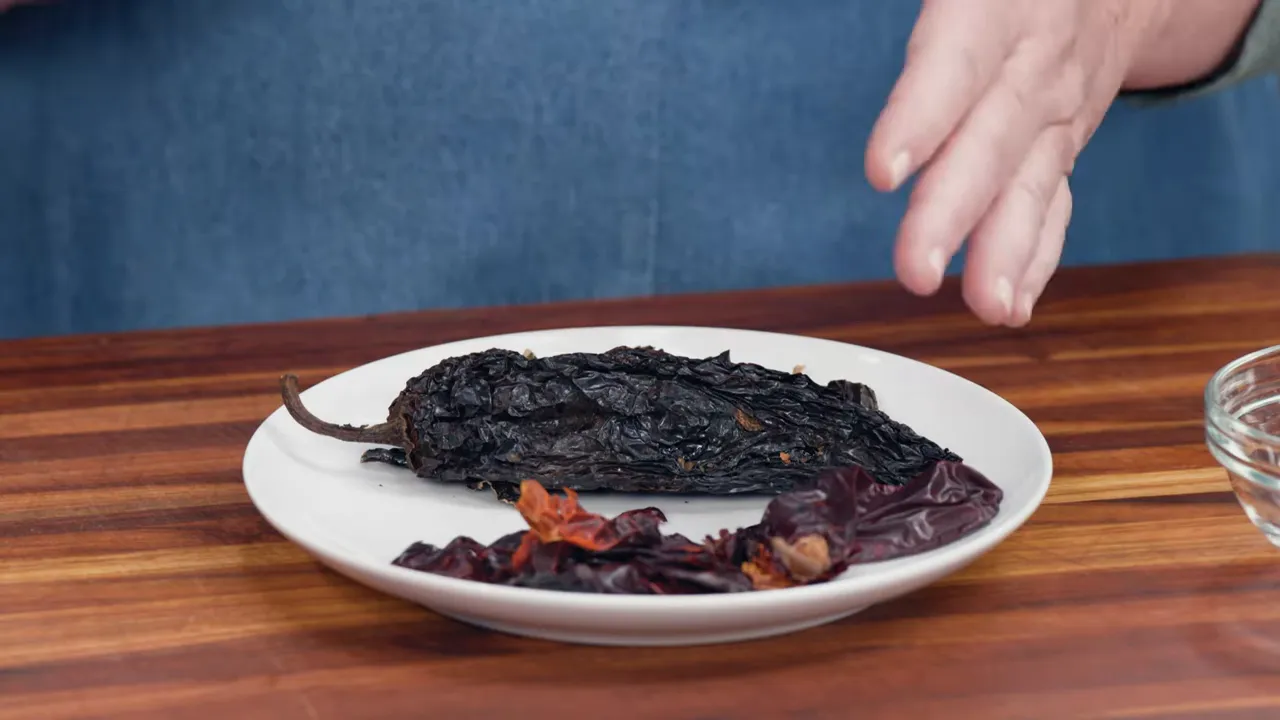 plate of dried chilies (ancho and guajillo) on a wooden cutting board next to small glass bowls