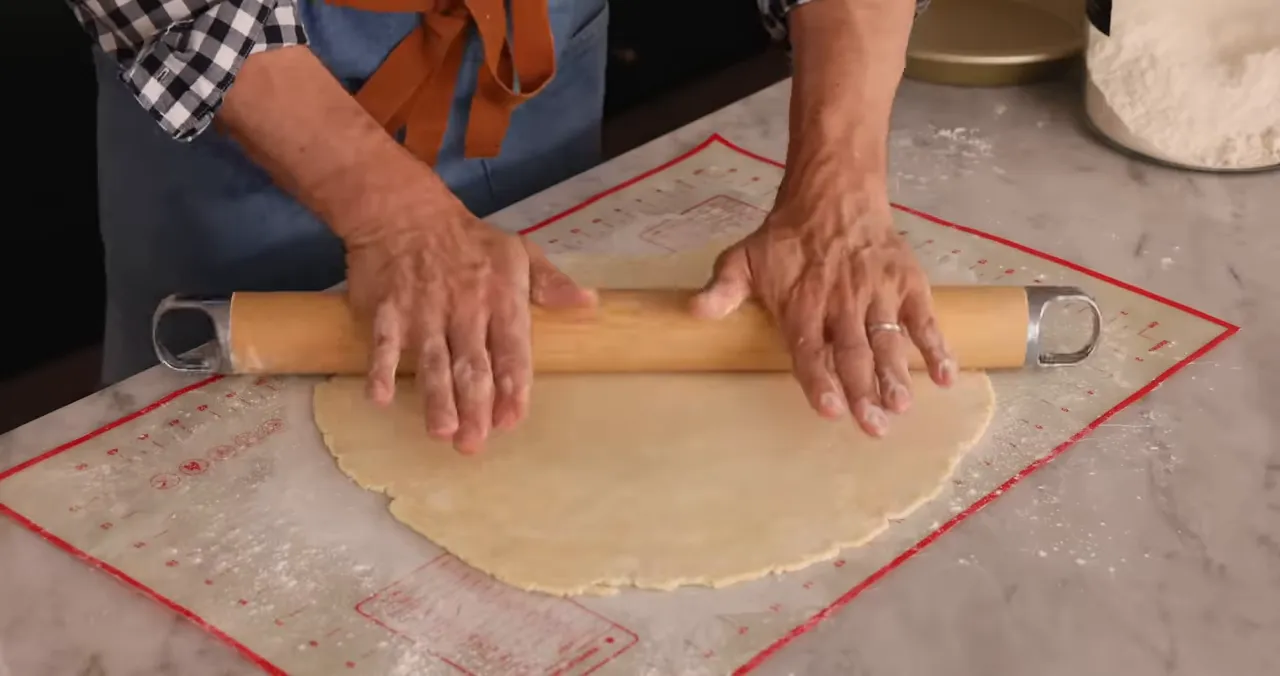 Rolling out pie dough on a pastry mat to prevent sticking