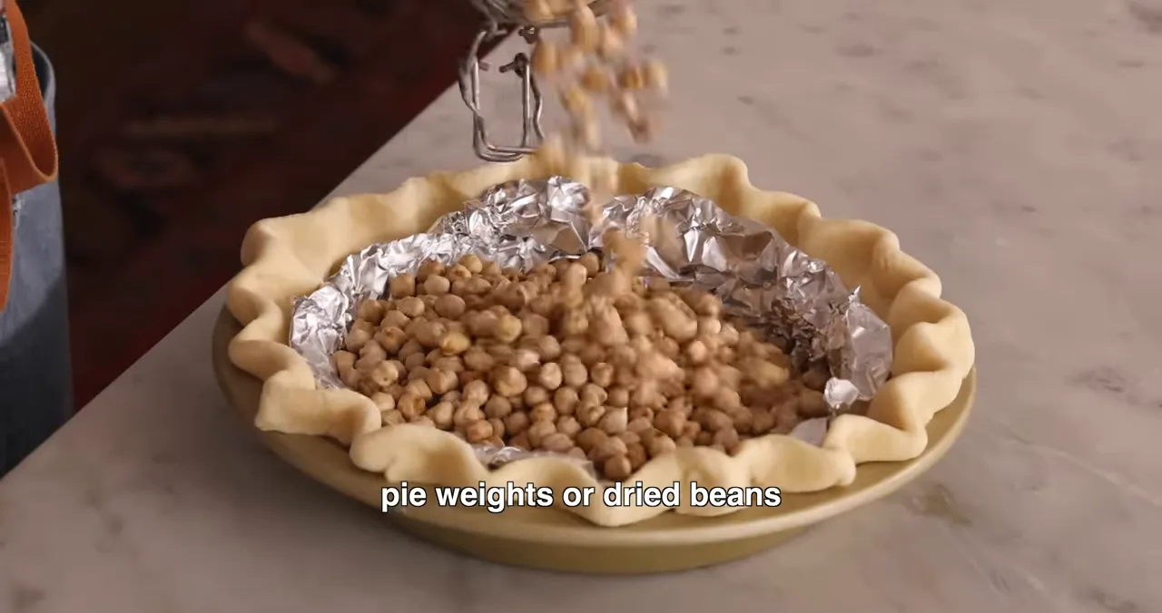 Parbaking the pie crust with foil and pie weights to prevent slumping