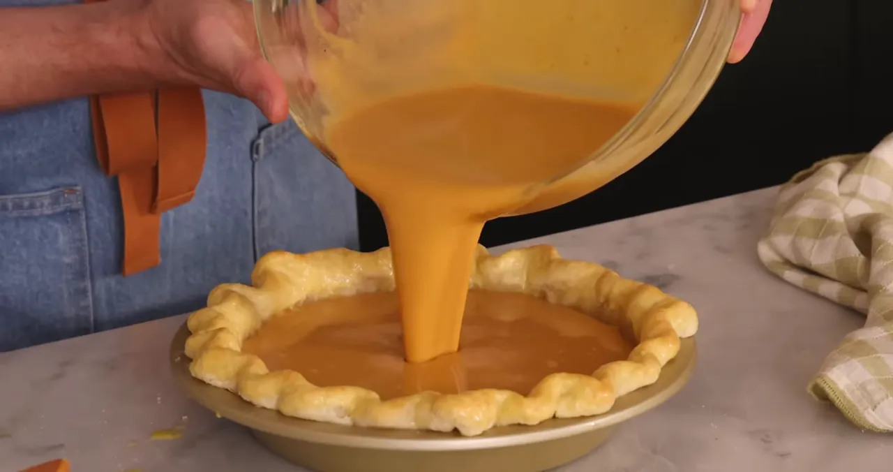 Pouring smooth pumpkin filling into the parbaked crust