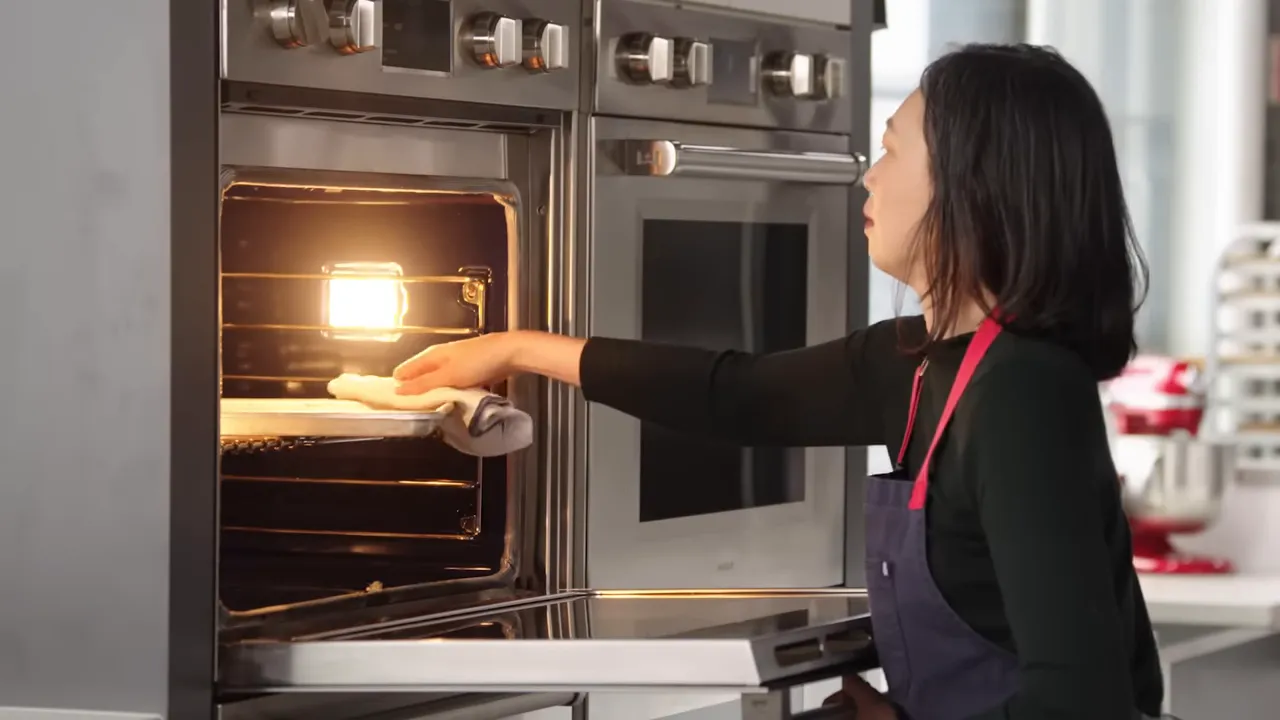 Hand sliding a tray of bacon into a lit preheated oven