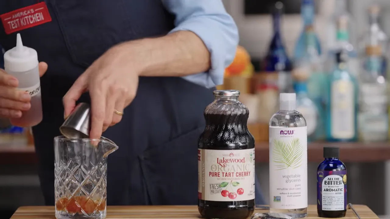 Hands pouring ingredients into a mixing glass; in the foreground are bottles of tart cherry juice, vegetable glycerin, and aromatic bitters.