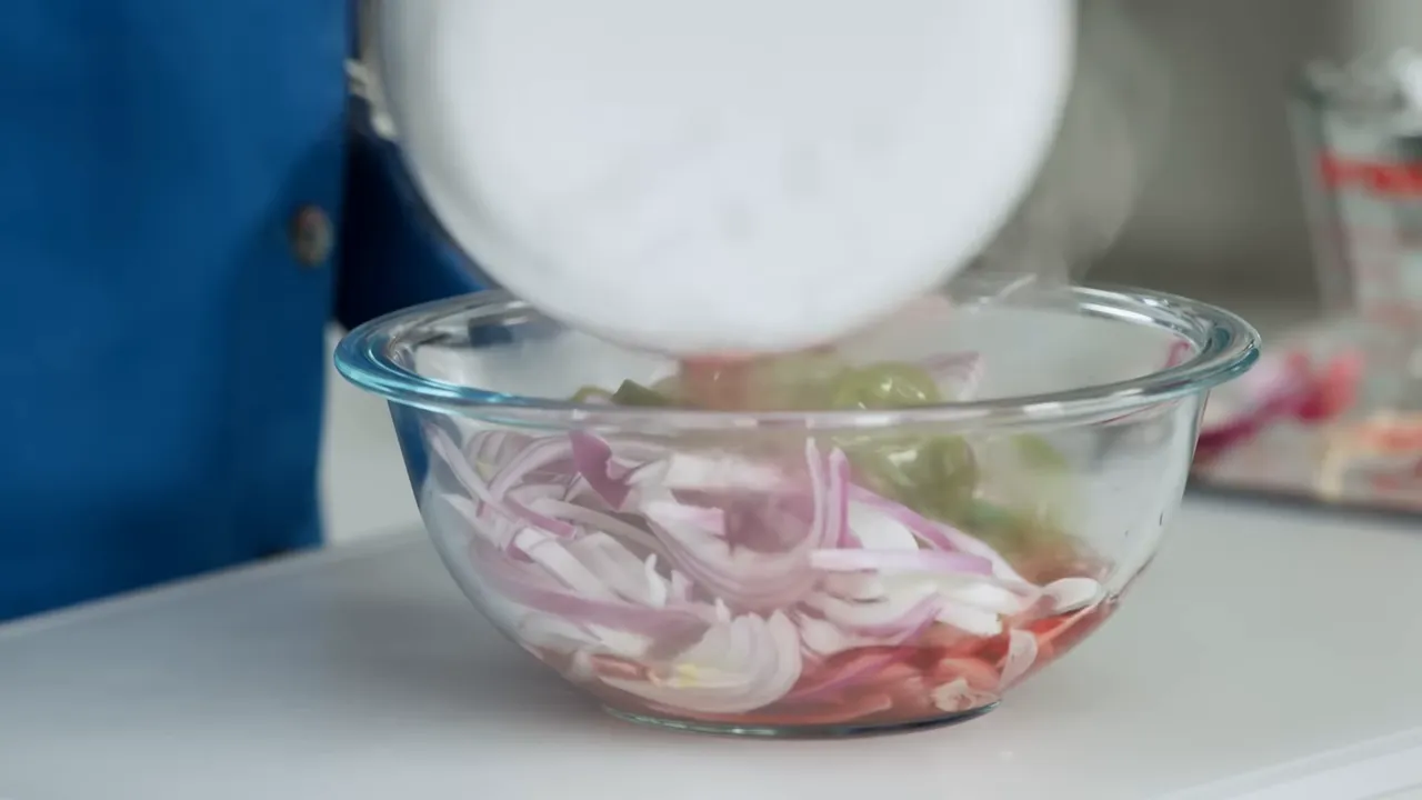 Pouring hot pickling liquid over sliced red onions