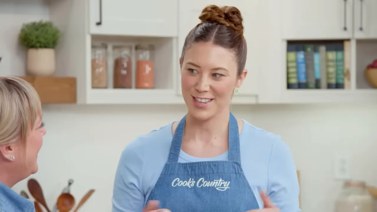 Cook's Country host in kitchen wearing apron and smiling