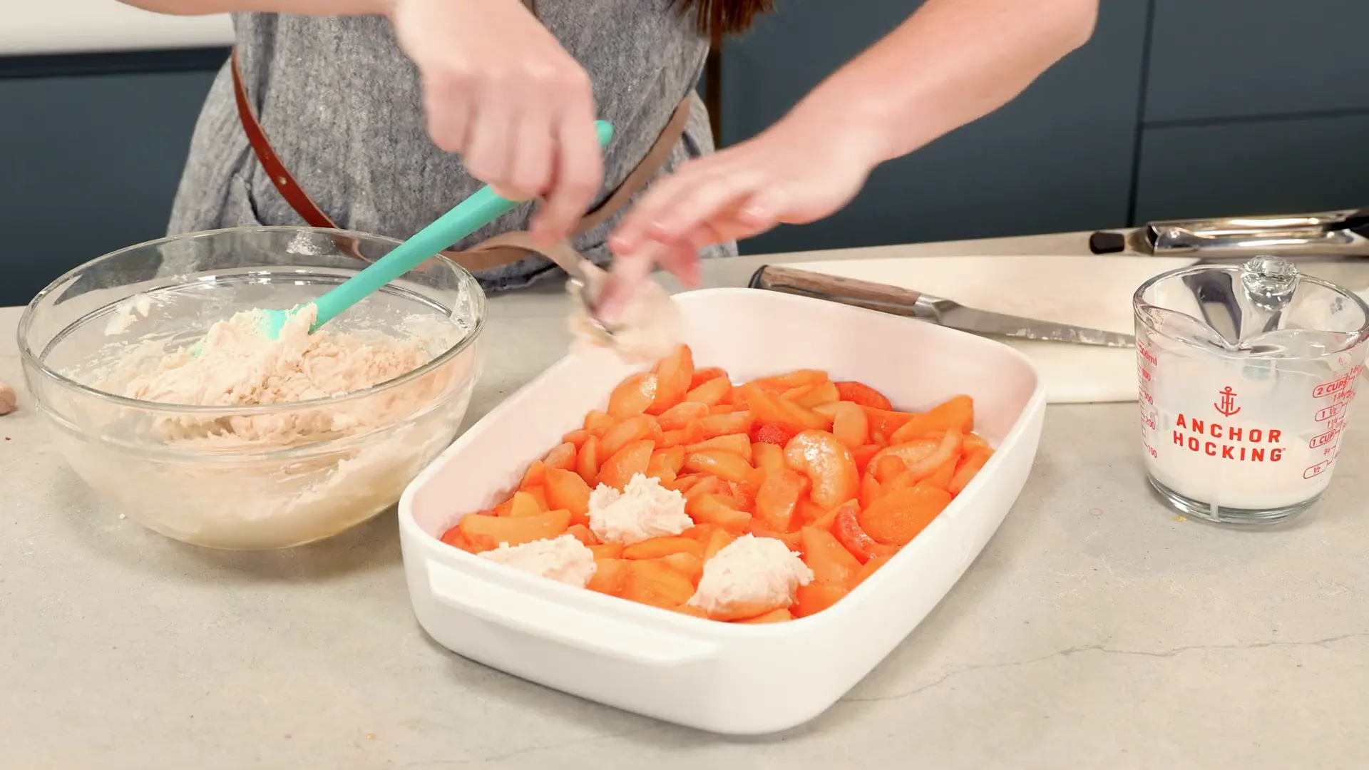 Dropping biscuit dough over peaches creating cobblestone top