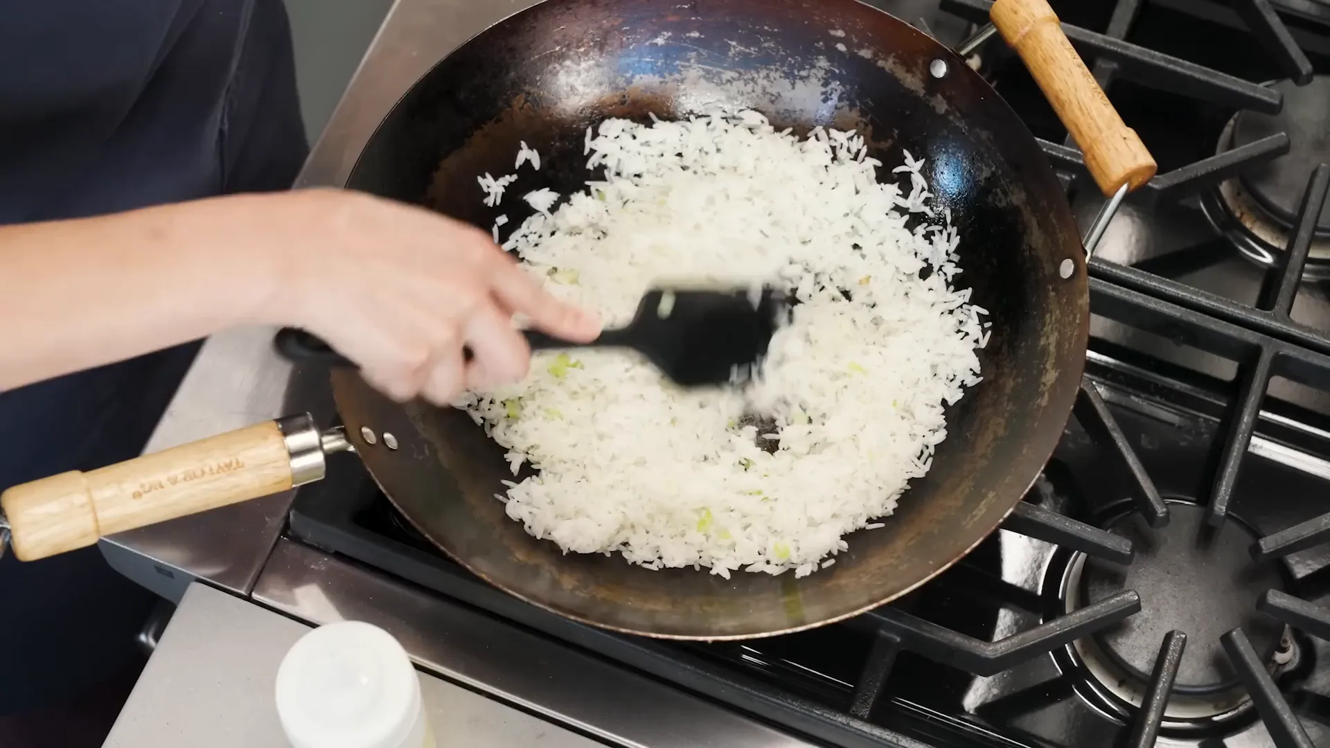 Rice being added to a hot wok and broken up with a spatula