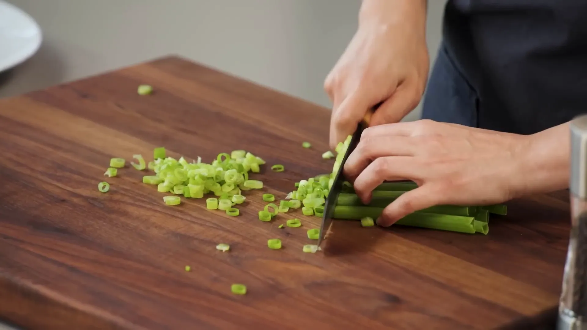 Hands slicing scallions, separating whites and greens