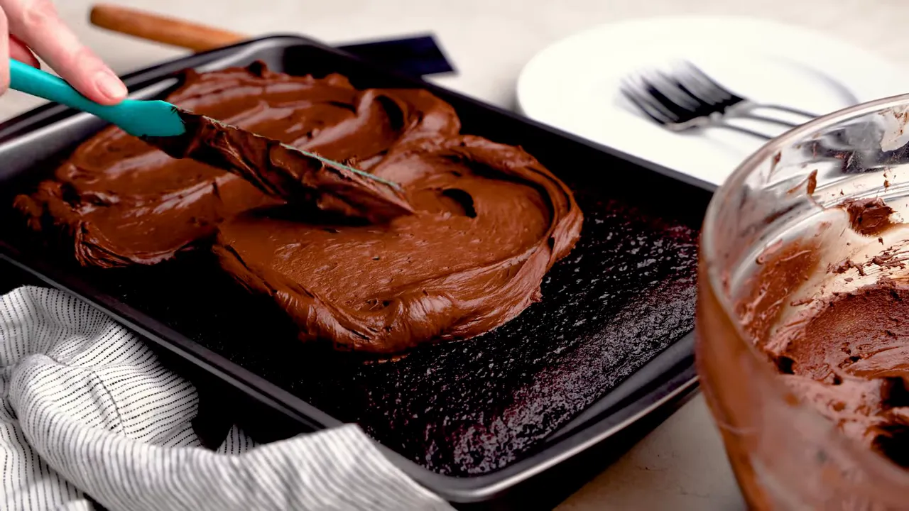 Frosting being spread over a cooled chocolate cake