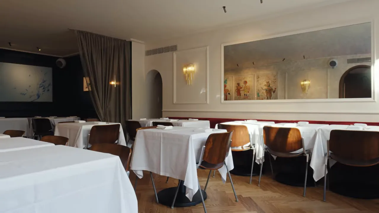 Le Chêne main dining room with white tablecloths, wooden chairs and large wall mirror