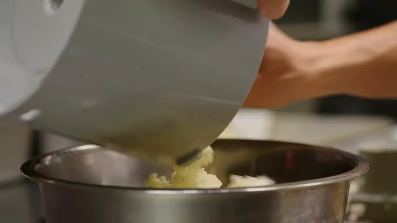 scraping cod and shrimp paste into mixing bowl