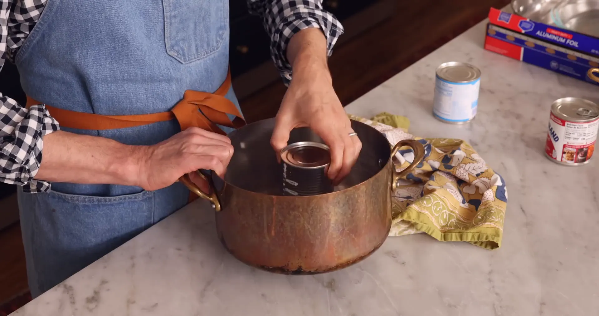 Cans of sweetened condensed milk submerged in a pot of water