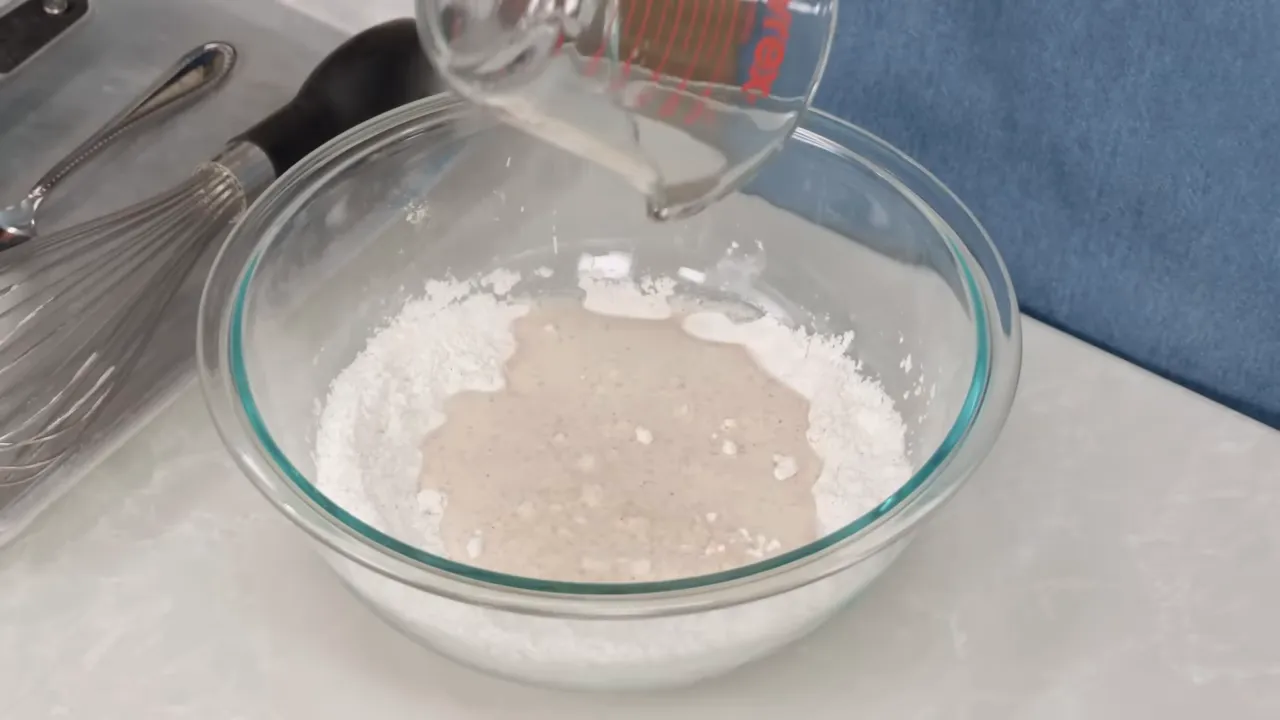 Pouring beer into a bowl of flour and cornstarch to make batter