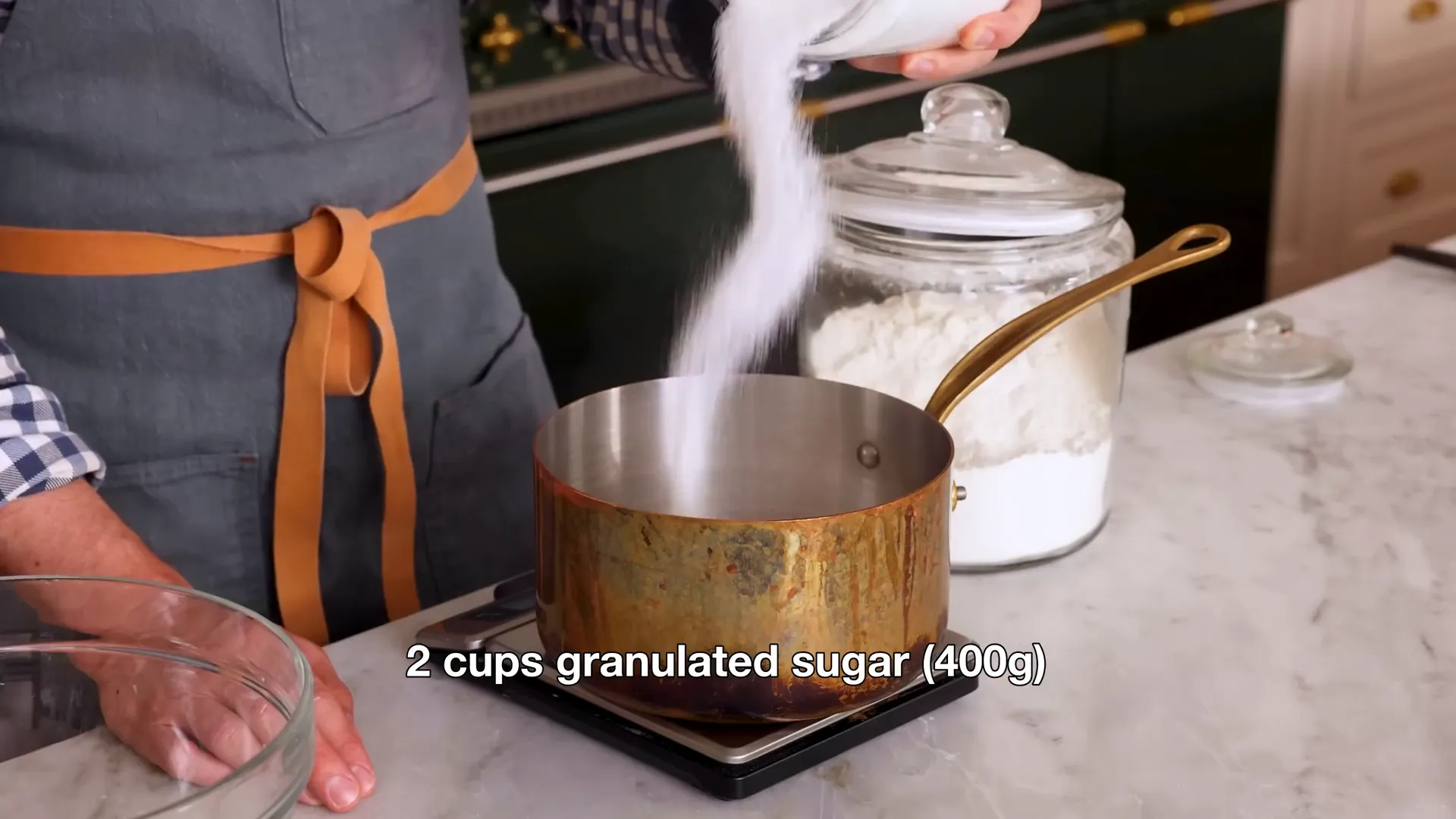 Ingredients for ermine frosting: granulated sugar and flour being added to a pan
