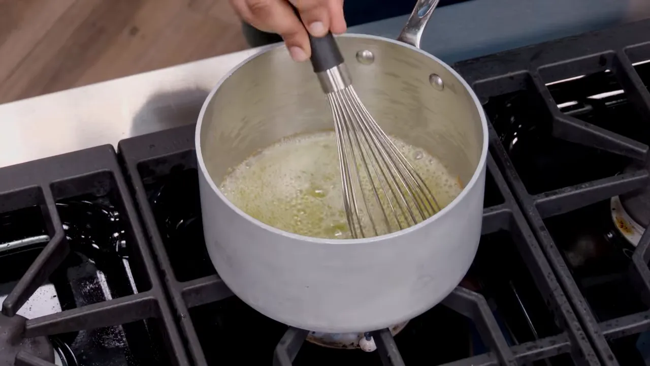 close-up of a whisk stirring foaming butter in a saucepan