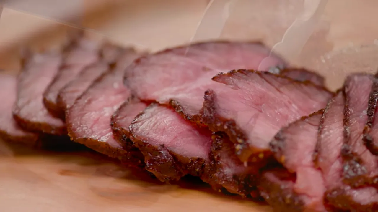 Close-up of multiple thin, medium-rare short-rib slices showing pink interior and browned edges