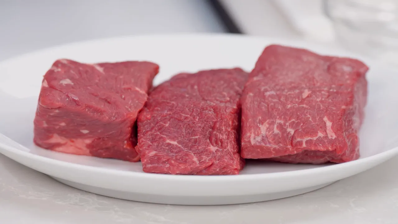 three raw boneless short ribs on a white plate, close-up