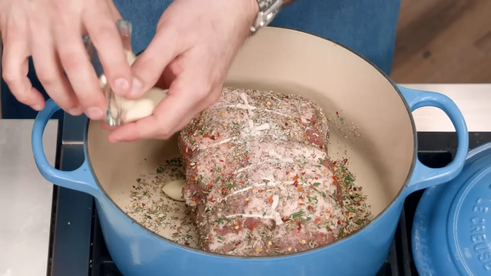 Seasoned pork roast in the Dutch oven with garlic cloves