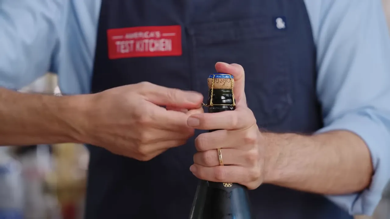 hands loosening champagne wire cage prior to opening