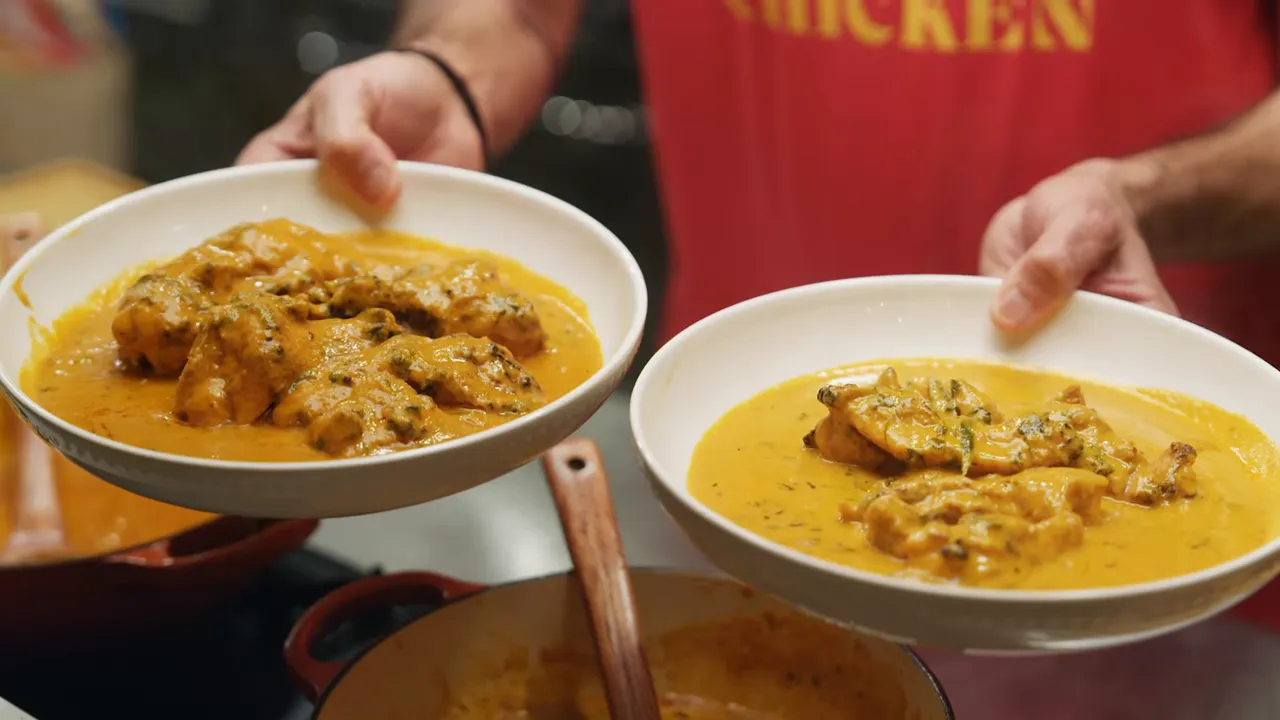 two bowls of finished butter chicken in creamy orange sauce being held for serving